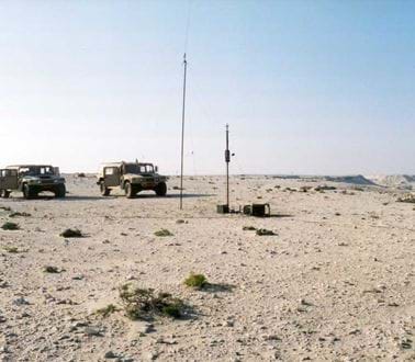 Military vehicles in a desert with antenna