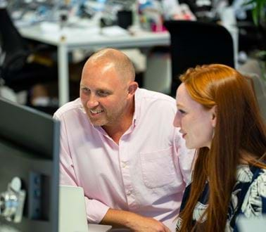 A man and two women work at a computer