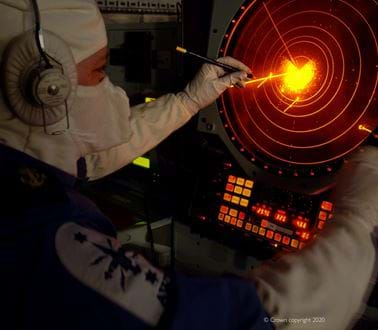 An operator in a balaclava observing a sonar screen