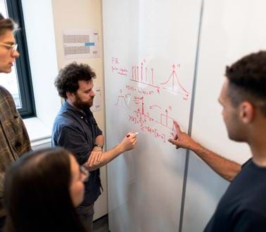 Engineers solve problems on a whiteboard