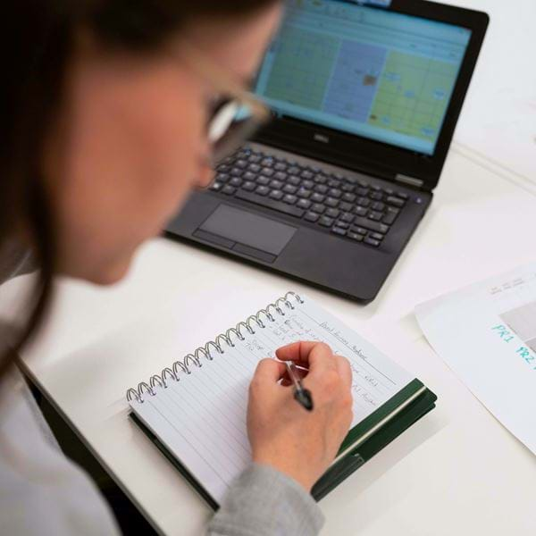 An engineer takes notes at a laptop