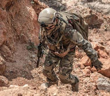 A soldier in desert camouflage climbing a mountain