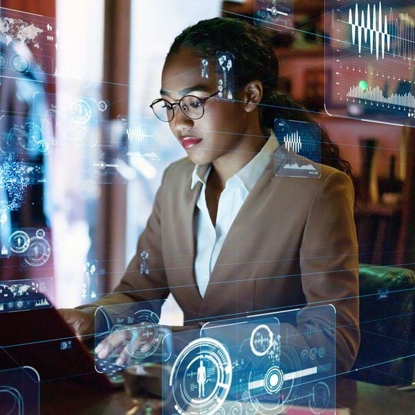 A woman works at a computer surrounded by technology graphics