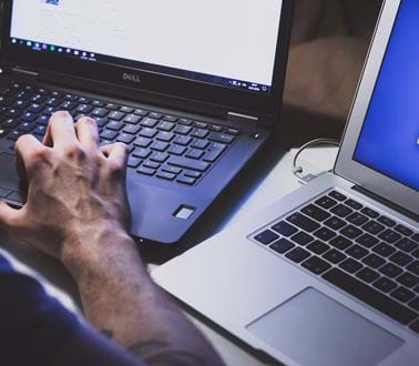 A man works at two laptops